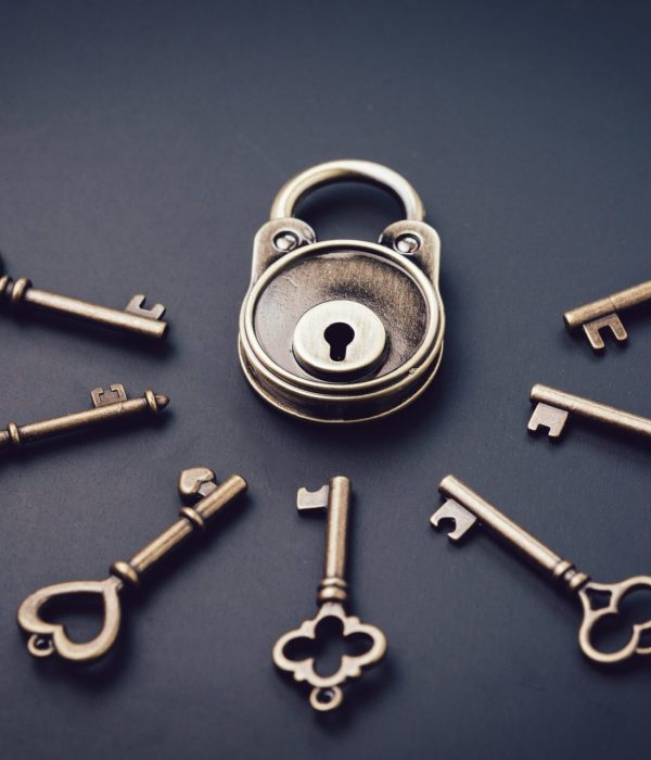 Security or secret protection concept, vintage brass padlock surrounded by multiple keys on a dark black background, internet hacker or cyber safety metaphor.